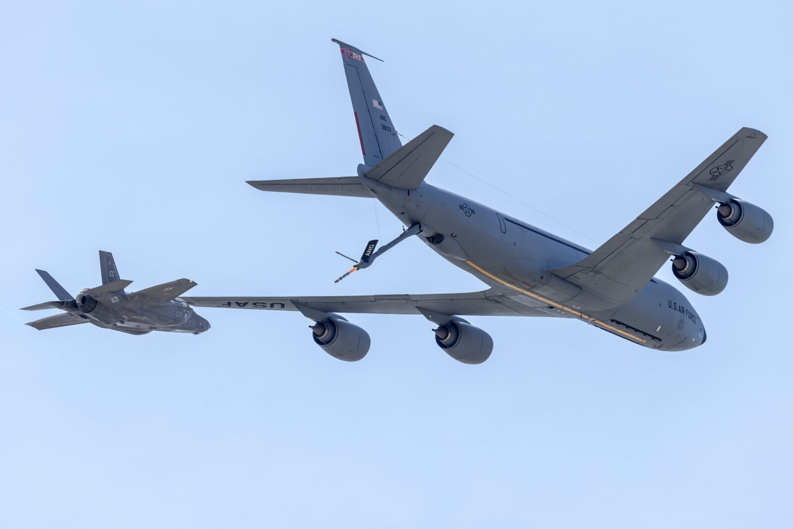 Two military aircraft flying in formation during an aerial refueling operation