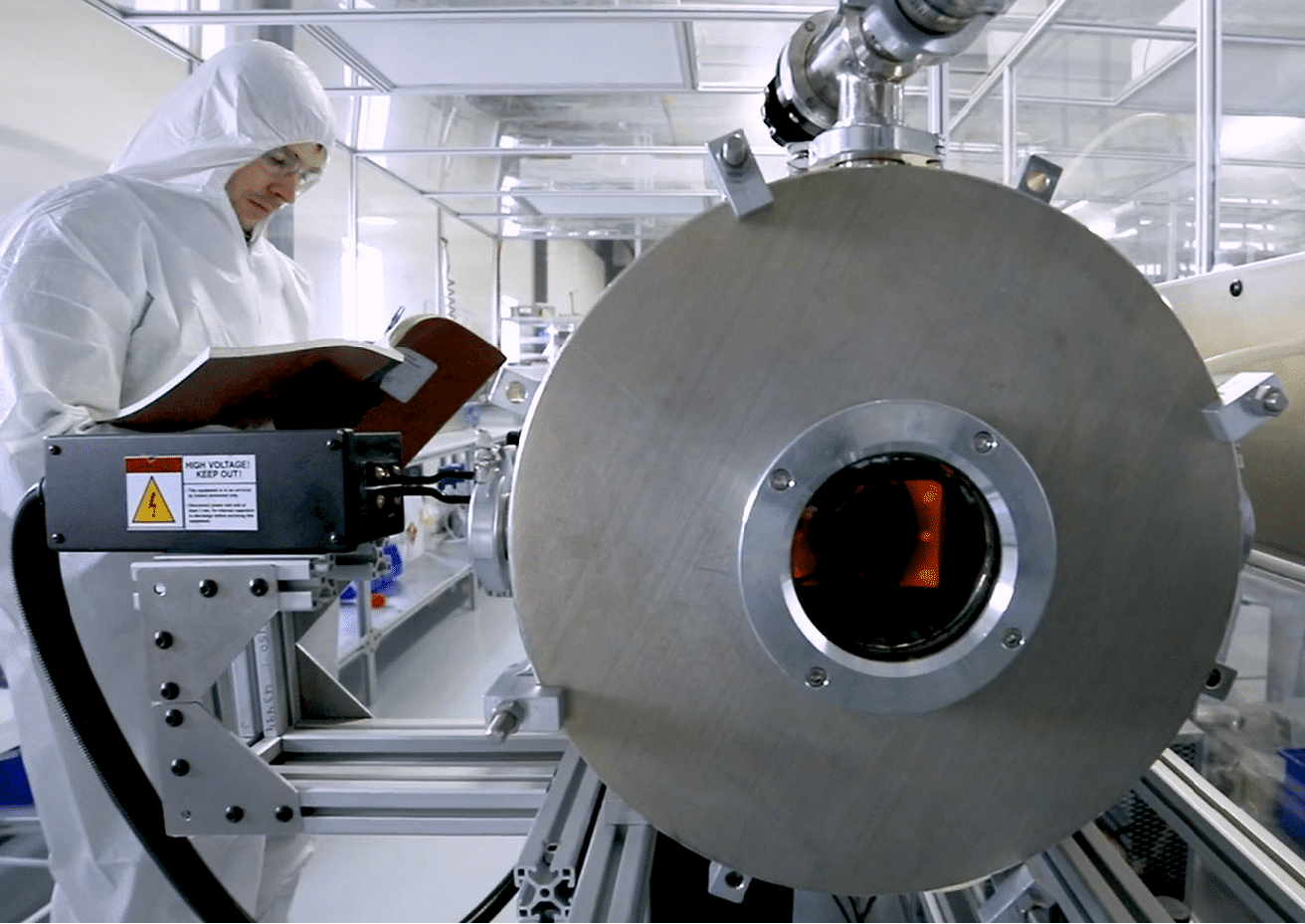 Technician operating a precision industrial machine inside a cleanroom environment